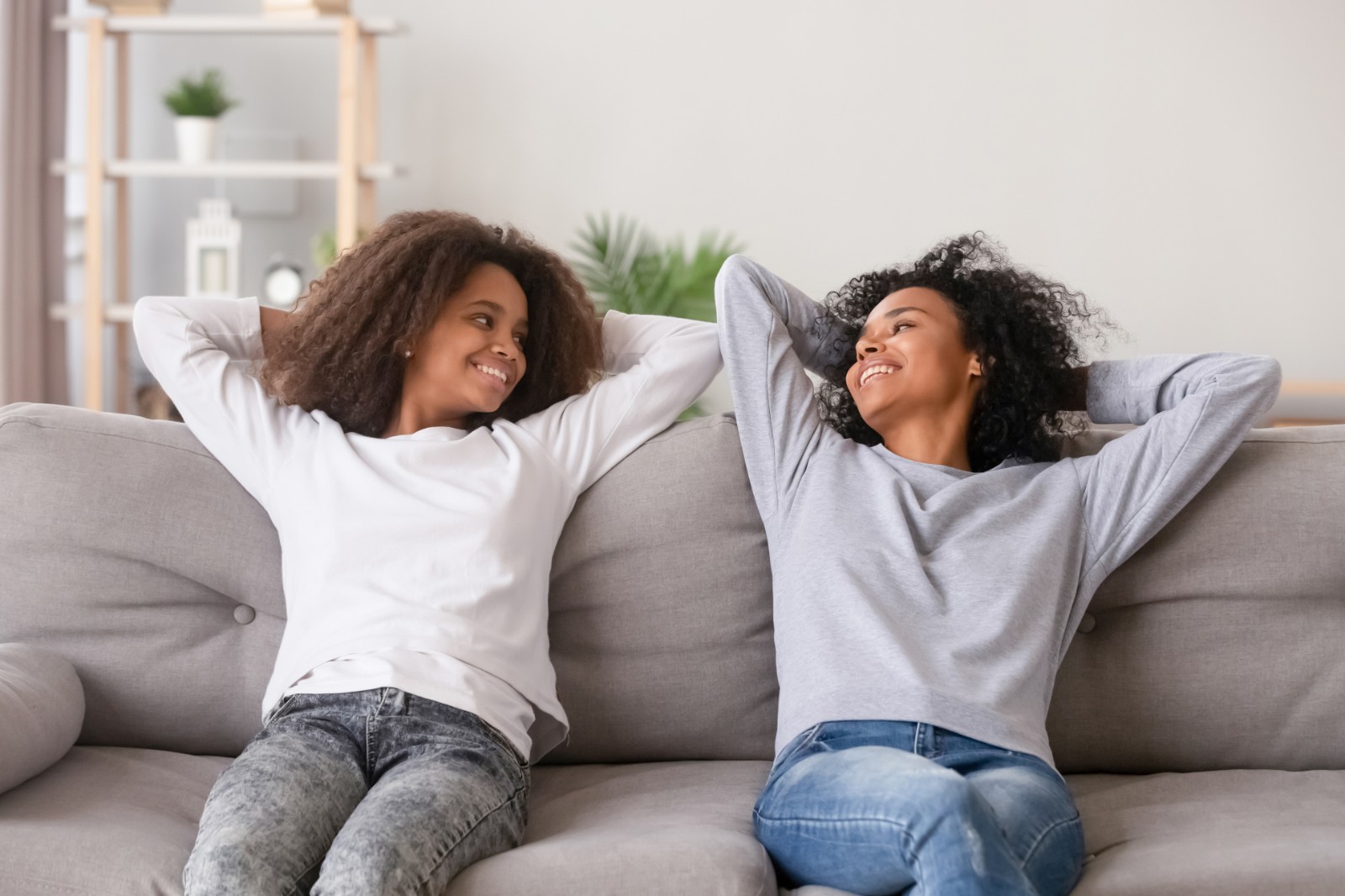 Mother and teen daughter relaxing on couch in comfort thanks to natural gas for home.